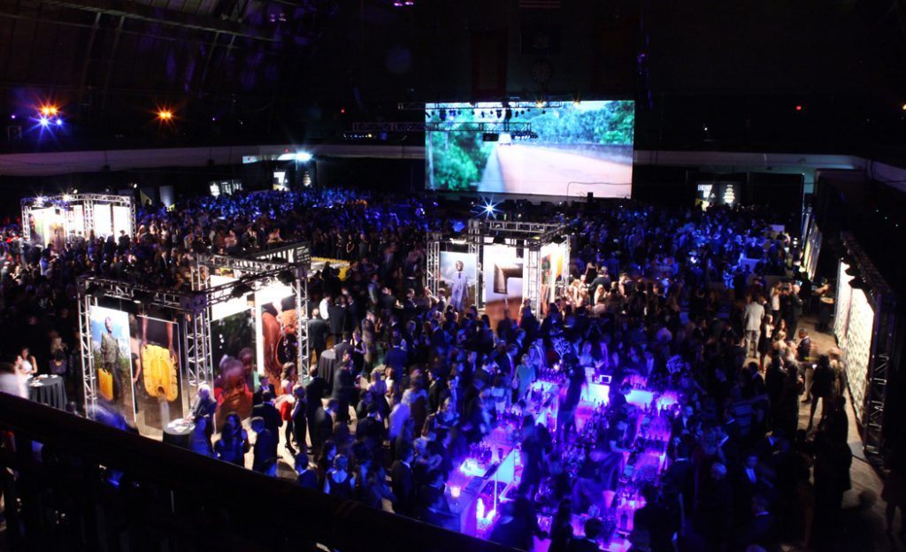 Aerial view of the packed charity: ball floor with exhibition booths and a large screen
