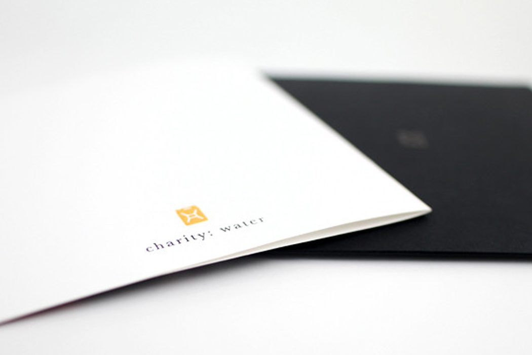 White card with the charity: water logo on top of the black folder