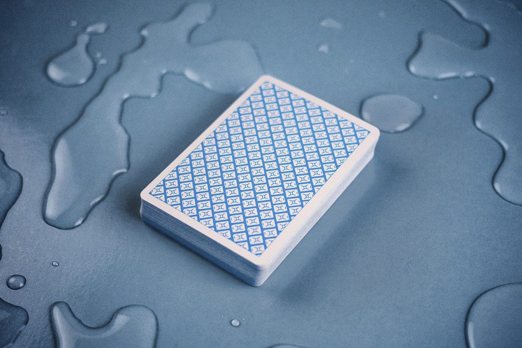 Back of a playing card deck with a blue water-drop pattern on a wet surface