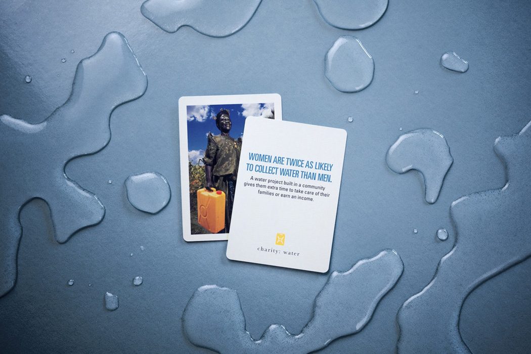 Playing cards with a photo and a statistic about women collecting water, on a wet surface