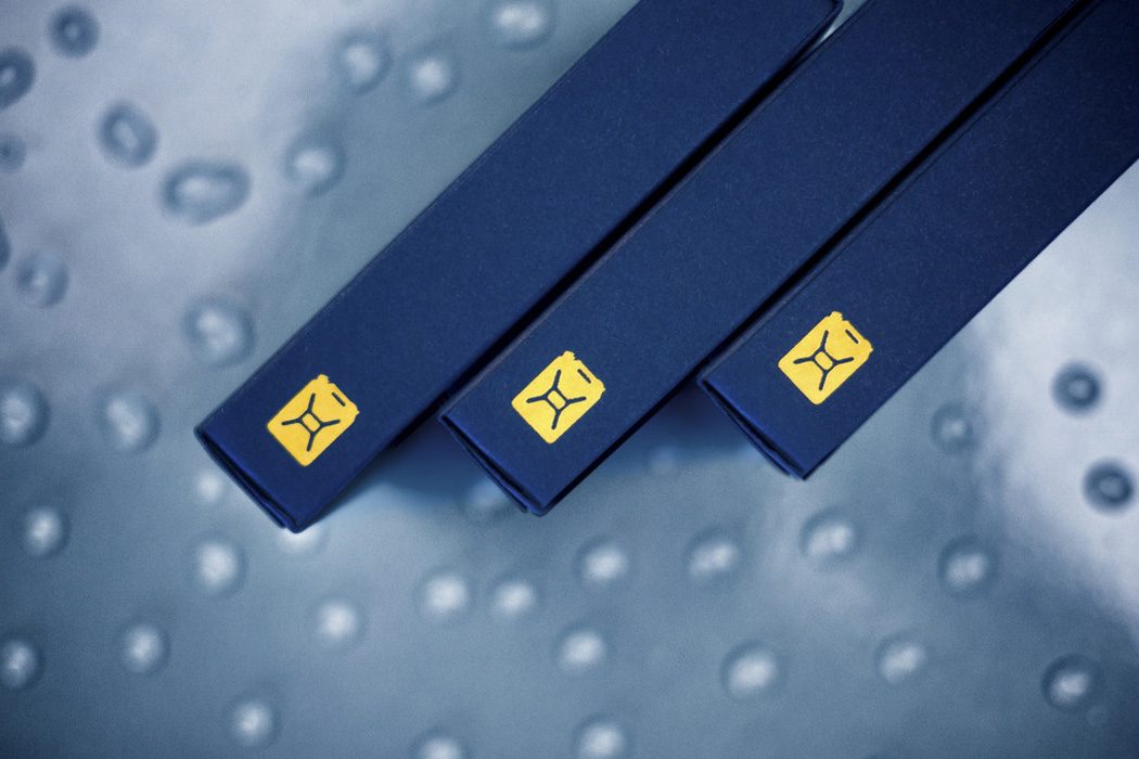 Three navy card boxes with yellow jerry can logos on a droplet-covered surface