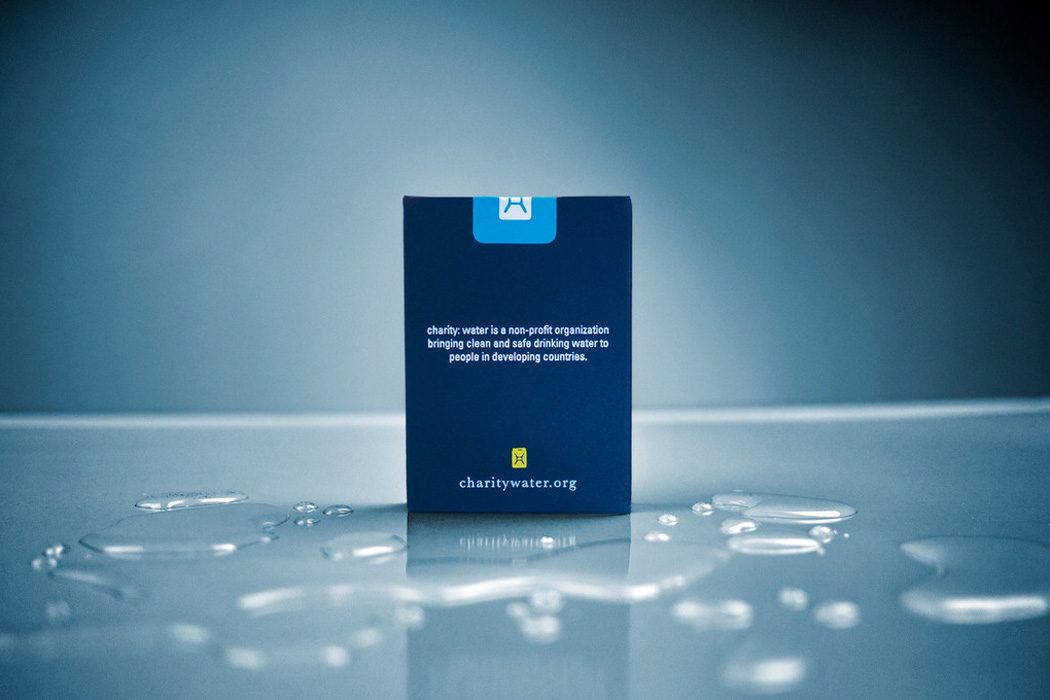 Navy charity: water playing card box standing in a puddle on a reflective surface
