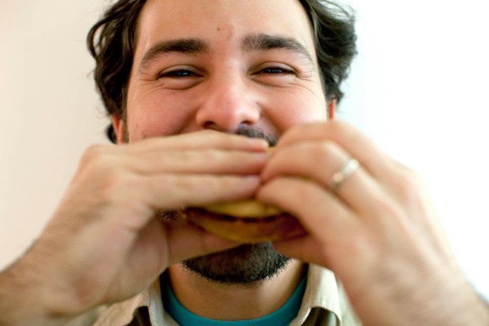 Greg taking a big bite of a sandwich