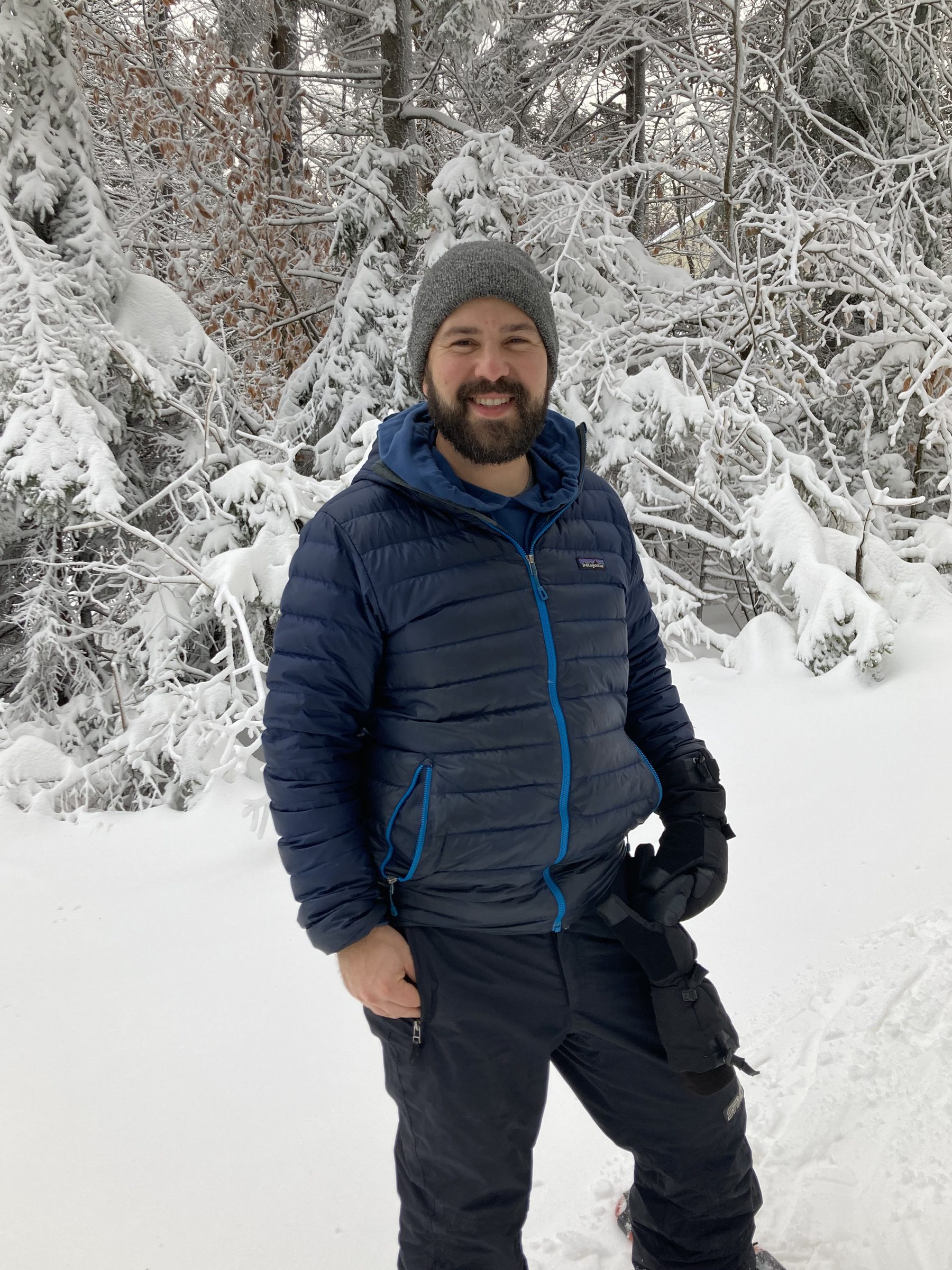 Greg smiling in a snowy forest