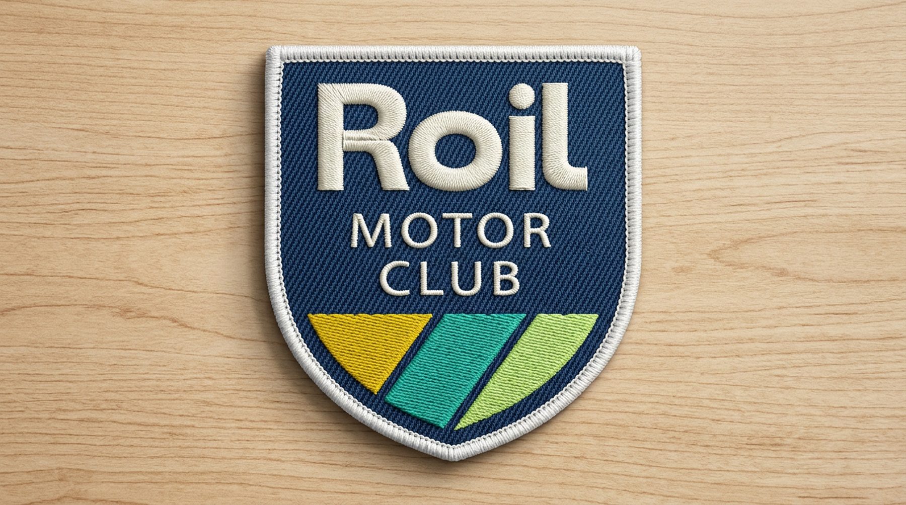 Shield-shaped Roil Motor Club patch on a wood surface
